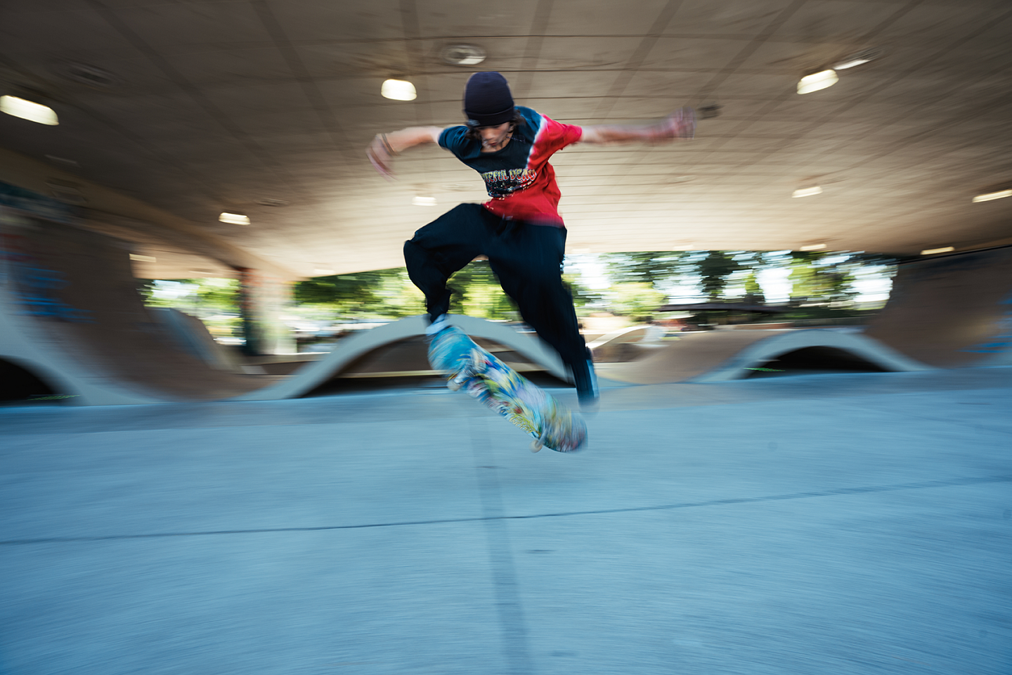 Youth on skateboarding does flip-board trick against urban backdrop