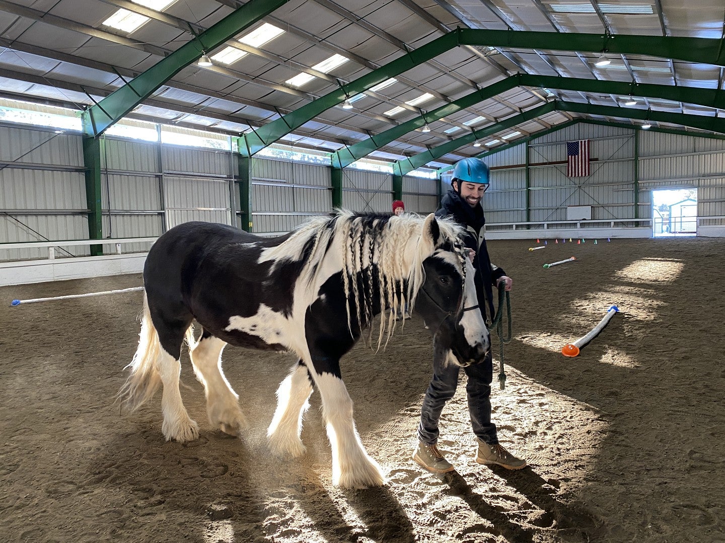 A student in a helmet walks a horse around a ring