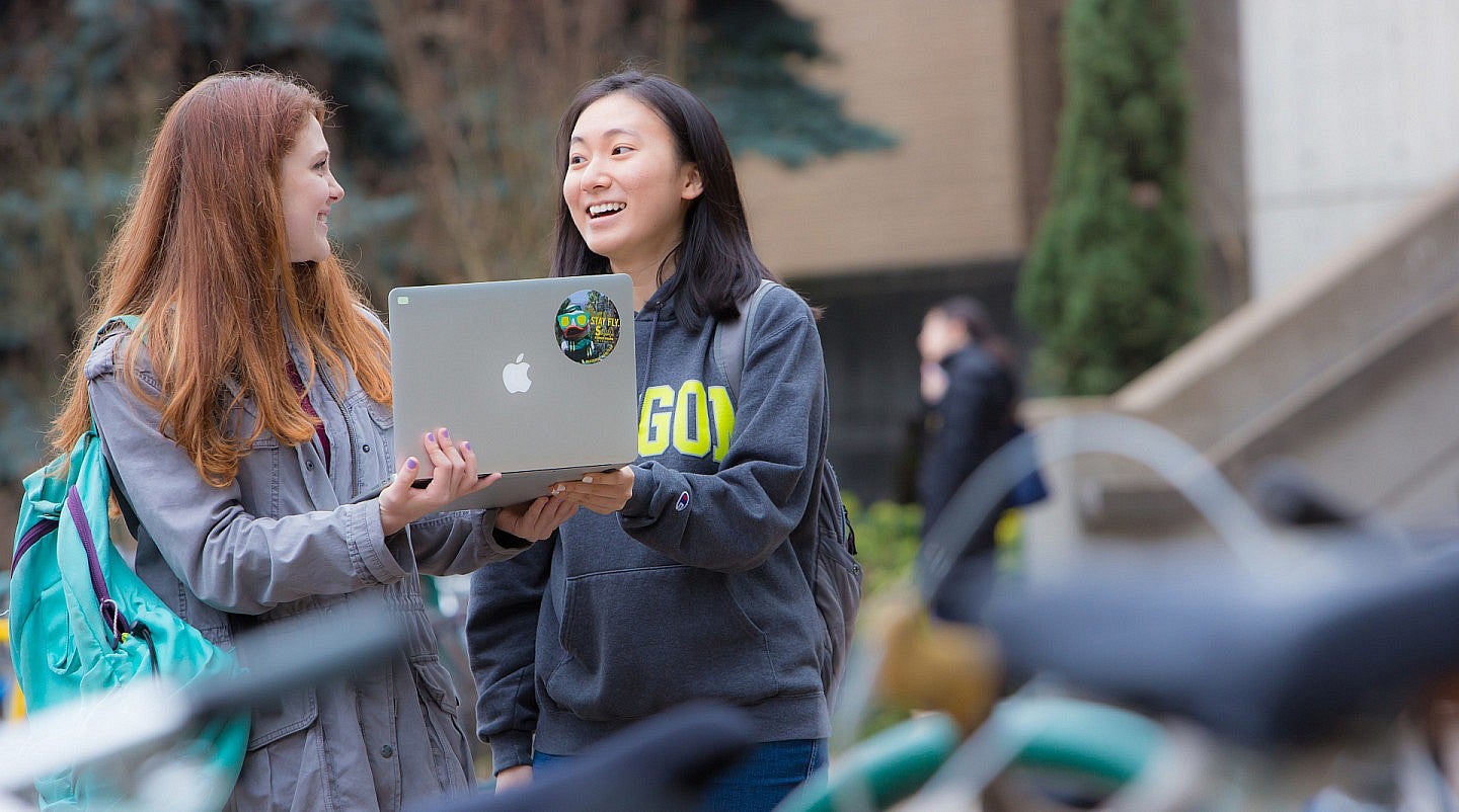 students view a laptop on the Eugene campus