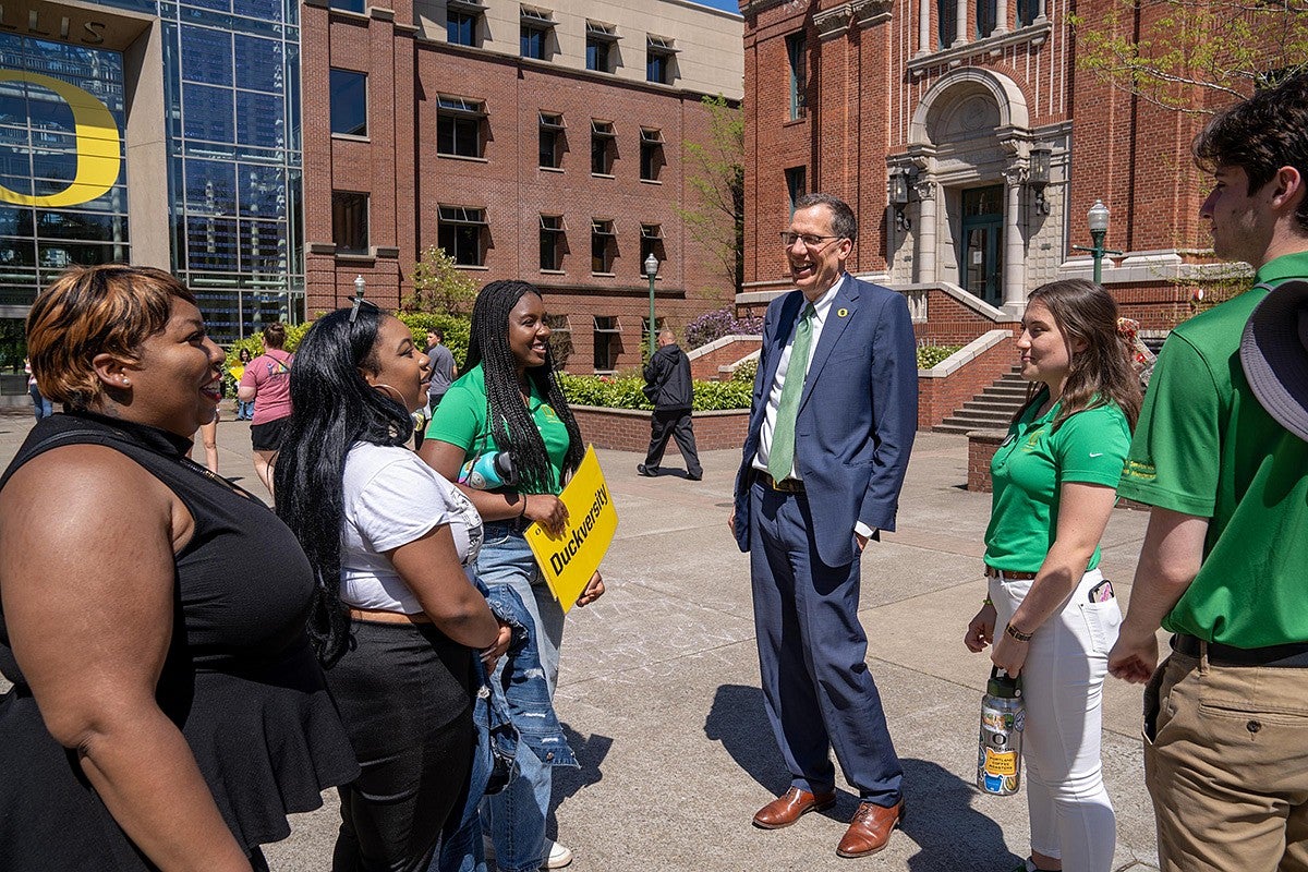 President Scholz talking with students outside the Lillis Business Complex