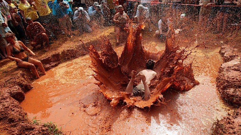 Person jumping into large mud puddle