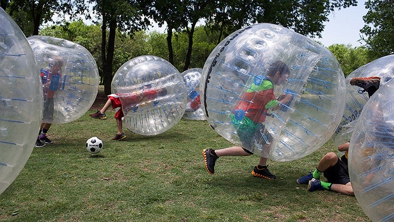People playing soccer while wearing transparent, spherical bubbles