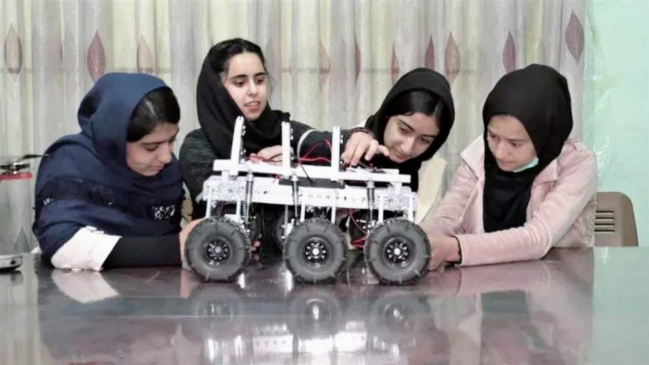 Saghar Salehi and other Afghan Dreamers work with a wheeled robot, all with head coverings