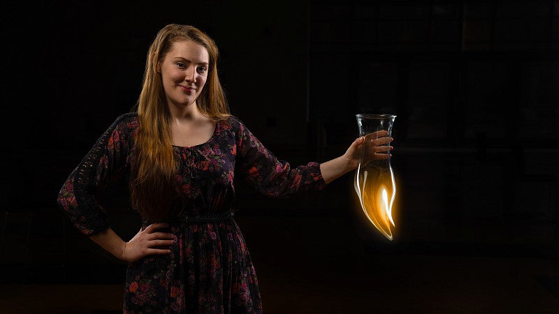 Nicole Wales holds a beaker that appears to melt into flame due to photo adaptation