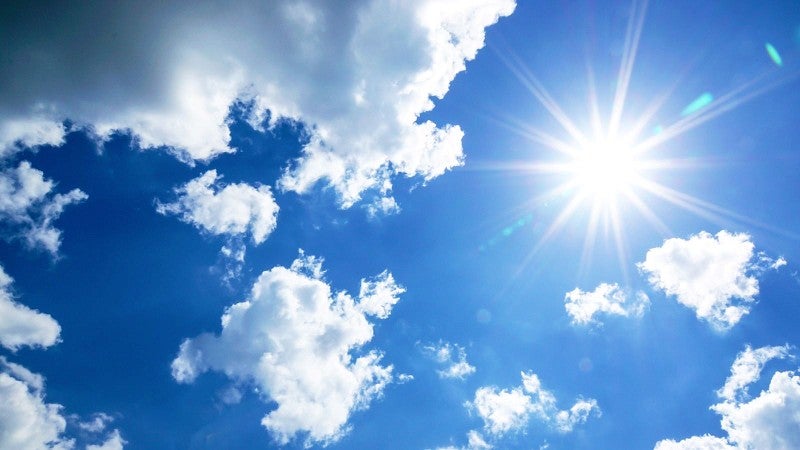 sunburst framed by blue sky and clouds