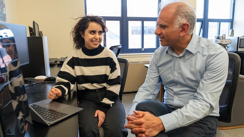 Saghar Salehi chats with Reza Rejaie at a computer in a classroom