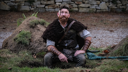 Thorfinn, looking reflective, sits in what appears to be an open grave