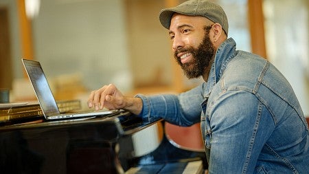 Black composer sits at piano keyboard