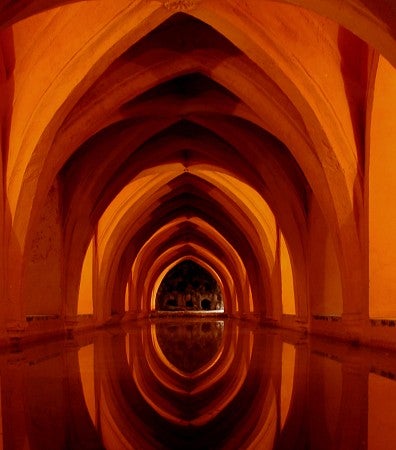 Reflection: red-hued image of religious structure with calm reflecting pool in foreground