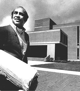 DeNorval Unthank Jr. in a vintage black-and-white photo, holding plans and photographed on UO campus