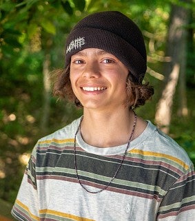 Participant Ashton smiles against a forest-like backdrop