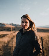 Author Helen Petersen portrait in a rural setting with fields and a fence