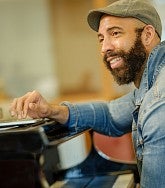 Black composer sits at piano keyboard