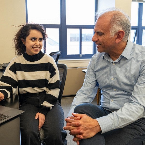 Saghar Salehi chats with Reza Rejaie at a computer in a classroom